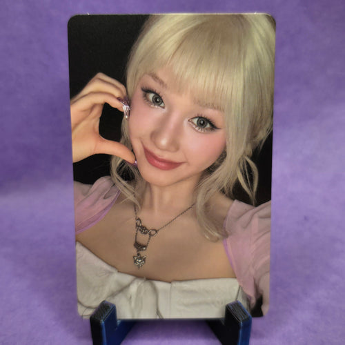 Person with blonde hair holding a phone on a purple background