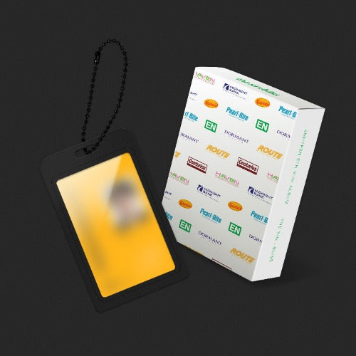 A black ID badge holder with a blank yellow placeholder card and a black chain, shown next to its white branded packaging box on a dark gray background.