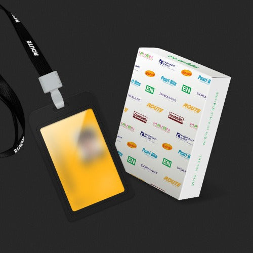 A black lanyard with a white plastic clip and a black ID badge holder containing a yellow card, shown next to its white branded retail box on a dark background.